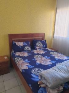 a bed with a blue comforter with flowers on it at Mousse Diop in Dakar