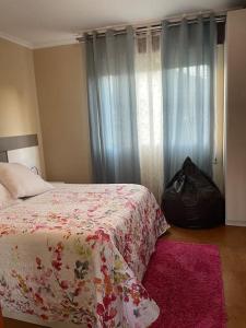 1 dormitorio con 1 cama con manta de flores y bolso negro en Casa con vistas a Portugal, en Arbo