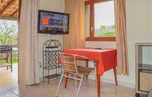カルカトッジョにあるAwesome Home In Calcatoggio With Wifiの赤いテーブルと椅子、テレビ付きのダイニングルーム