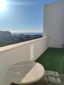 Atico con piscina, golf, vistas al mar في توري دي بيناغالبون: شرفة مع طاولة وإطلالة على المحيط