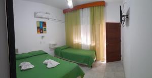 Habitación con 2 camas verdes y ventana. en Hotel Ciudad del Sol en Termas de Río Hondo