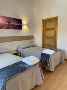 a hotel room with two beds and a door at Hostal A Cantina de Renche in Renche