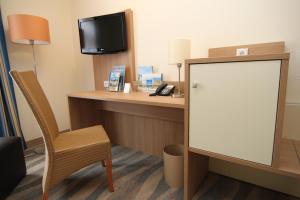 a room with a desk with a tv and a chair at Inselhotel Bruns in Norderney +17 photos