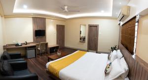 a hotel room with a bed and a desk and a television at HOTEL BRAHMAPUTRA MADHUKALYA in Guwahati +17 photos