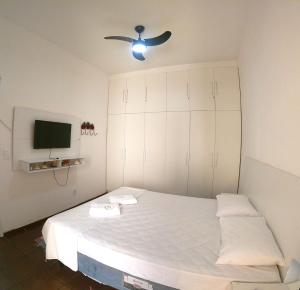 a bedroom with a white bed with a ceiling fan at Apartamento Cabo Frio in Cabo Frio