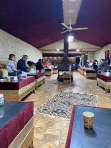 hol z ludźmi siedzącymi przy stołach i kominkiem w obiekcie Taj Wadi Rum camp w mieście Wadi Rum