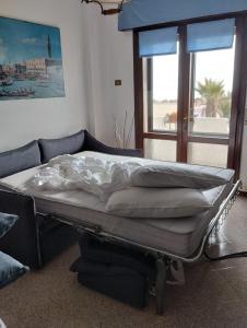 a bed sitting in a room with a couch at Appartamento Frontemare Azzurra in Caorle