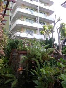 un immeuble d'appartements avec des plantes devant lui dans l'établissement Daisy Residence, à Jomtien Beach