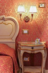 a bedroom with a bed and a nightstand with two lamps at Apostoli Palace in Venice