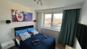 une chambre avec un lit bleu et une fenêtre dans l'établissement Resort Apartamenty Klifowa Rewal 55, à Rewal 37 autres photos