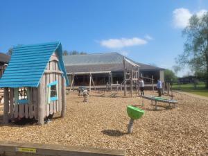 un parque infantil con un edificio y una estructura de juegos en Nightingale en South Cerney