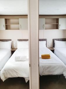 2 camas en una habitación con sábanas blancas y una toalla amarilla en Nightingale, en South Cerney