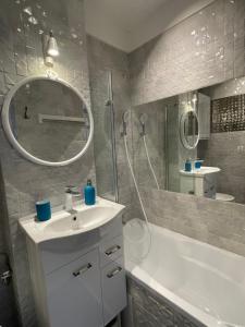 a bathroom with a sink and a shower and a mirror at Apartament Pomarańczowy in Warsaw