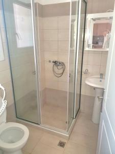 a bathroom with a shower with a toilet and a sink at BELLA De LUX APTS in Ipsos