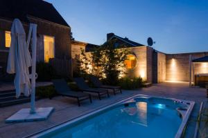 um quintal com uma piscina e cadeiras e uma casa em Wellnessvakantiehuis Victorello em Heuvelland