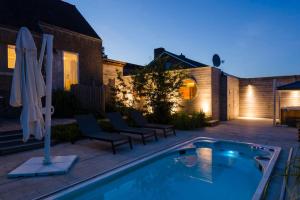 a backyard with a swimming pool and chairs and a house at Wellnessvakantiehuis Victorello in Heuvelland