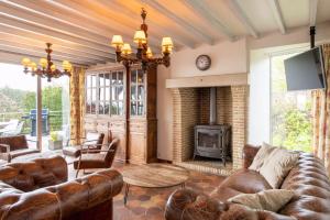 a living room with leather furniture and a fireplace at Wellnessvakantiehuis Victorello in Heuvelland