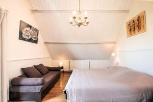 a bedroom with a bed and a couch and a chandelier at Wellnessvakantiehuis Victorello in Heuvelland +14 photos