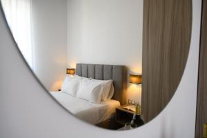 une chambre d'hôtel avec un lit et un miroir dans l'établissement Amalphi Corfu City Living by Konnect, à Corfou