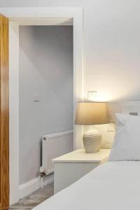 1 dormitorio con cama y mesita de noche con lámpara en Ardoyne Lodge 'Sleeping 4 Guests' en Belfast