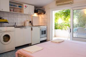a kitchen with a stove and a washing machine at Apartments Pomalo in Makarska