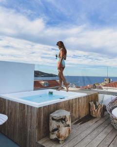 a woman walking on the edge of a swimming pool at Castel Abaso Boutique Apartments in Andros