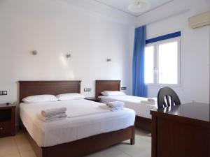 Habitación de hotel con 2 camas y escritorio en Sea Front Studios Old Town, en Rethymno