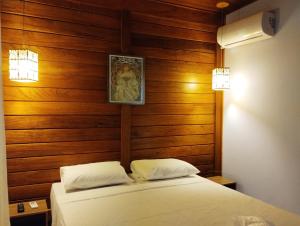 um quarto com paredes de madeira e uma cama com lençóis brancos em VIA SPE - Pousada em Belo Horizonte