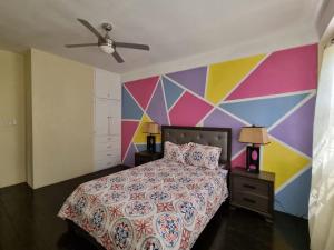 kolorowa sypialnia z łóżkiem i kolorową ścianą w obiekcie Tropical Suites w mieście Choiseul