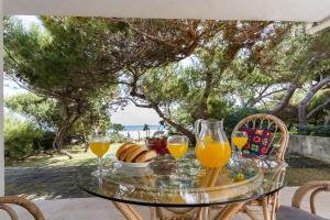 una mesa de cristal con vasos de zumo de naranja y pan en Playa de Muro - Nordvillas, en Muro