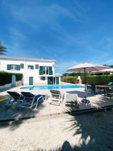 una casa con piscina con sedie e ombrellone di Good Vibes Villa ad Aljezur