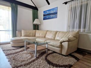 un soggiorno con divano e tavolo in vetro di Villa Felícia a Balatonszepezd