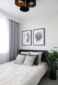 Apartament Kraszewskiego في بياويستوك: غرفة نوم بسرير ابيض بثلاث صور على الحائط