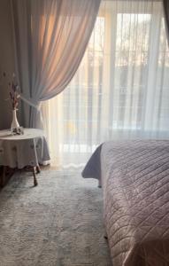 ein Schlafzimmer mit einem Bett und einem Tisch neben einem Fenster in der Unterkunft Tamerlan in Chmelnyzkyj