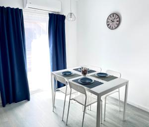 a dining room table with chairs and a clock on the wall at Mira new appartment in Otopeni near airport in Otopeni +12 photos
