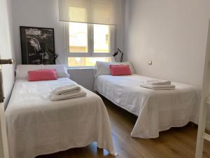 two beds in a room with white and red pillows at Contemplando la Catedral by Exclusive Burgos Apartments in Burgos