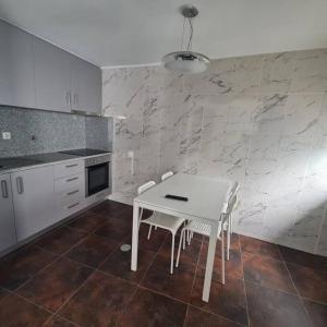 a kitchen with a white table and chairs in it at Casa de Férias_As Oliveiras II in Espinho