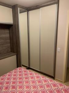 ein Schlafzimmer mit Glastüren und einem rosa Teppich in der Unterkunft Apartamento do Aconchego in Bento Gonçalves