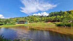 a body of water with a house in the background at Espaço Canto in Santo Antônio do Pinhal