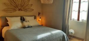 um quarto com uma cama com almofadas brancas e uma janela em Aux coeurs du Méjean 