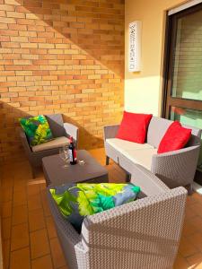 a patio with wicker chairs and tables and a brick wall at Sunset Lagos Apartment in Lagos