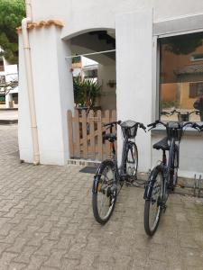 Deux vélos sont garés à l'extérieur d'un bâtiment. dans l'établissement T2-3 cabine Les YUCCAS 200 m plage du Boucanet Rive Droite Grau du Roi idéal 2-4 pers, au Grau-du-Roi