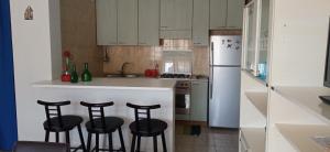 a kitchen with three bar stools and a white refrigerator at Home Tropicana in Mascali