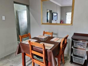 mesa de comedor con 4 sillas y espejo en 9 Levubu Cottages en Polokwane
