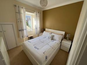 a bedroom with a large white bed and a window at Fantastic 3 bedroom holiday home in Millport