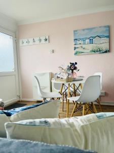 a dining room with chairs and a table and a painting at “BLISS ON THE BAY ” chalet in Sandown Bay Holiday Park in Sandown
