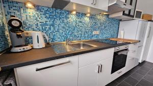 a kitchen with a sink and a blue tiled wall at Appartement Vanille, Ferienwohnung mit eigenem Eingang, wie ein kleines Haus in Bad Salzuflen
