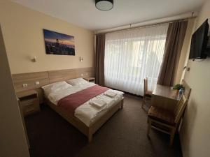 a bedroom with a bed and a desk and a window at Mocca House in Raszyn