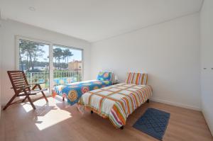 ein Schlafzimmer mit einem Bett, einem Stuhl und einem Fenster in der Unterkunft Aroeira Villa w/ Pool near Beach, By TimeCooler in Aroeira