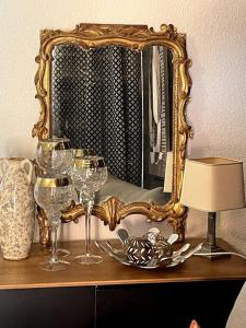 una mesa con copas de vino y un espejo en Le Chic, en Lourdes